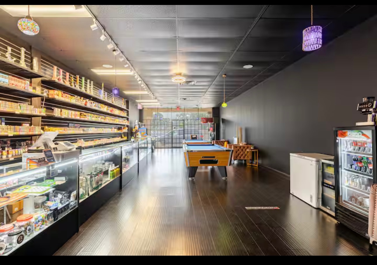 Looking down the shop floor past the counter cases to the front windows, with the glass-door drinks cooler on the right.
